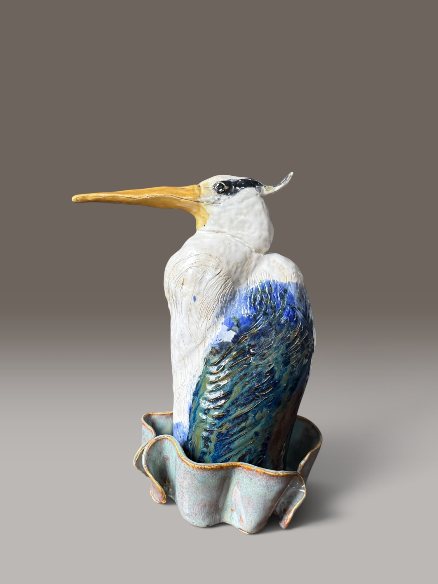 The Long Wait, a heron with its neck drawn down into a scalloped basin